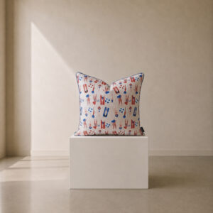 Decorative scatter cushion featuring a playful beach-themed print with illustrated swimmers, umbrellas, and beach accessories in coral red and blue on a soft neutral background.